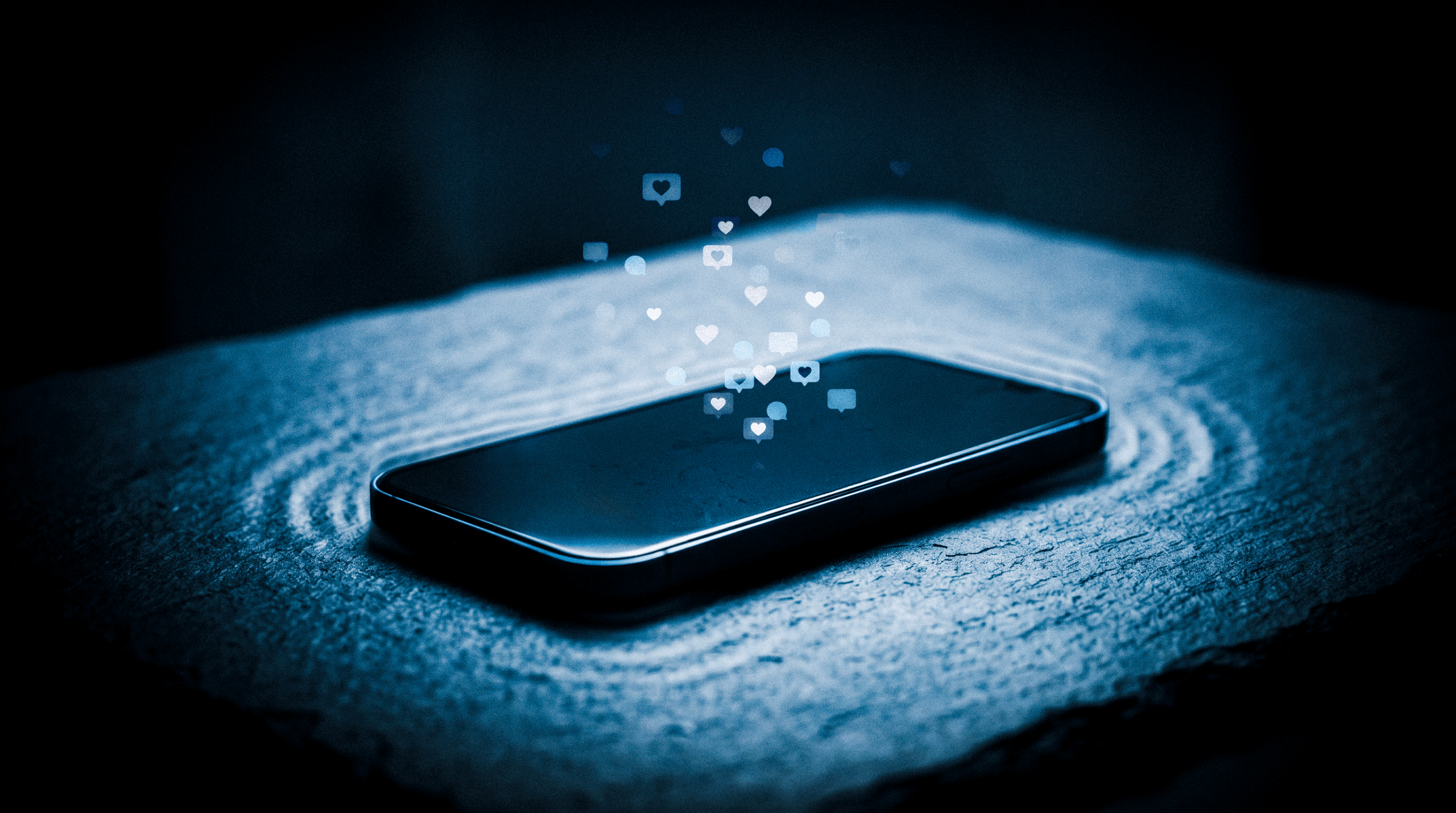 Telemóvel sobre uma mesa escura a vibrar suavemente enquanto bolhas de notificação brilhantes flutuam e desaparecem no ar, simbolizando a vacuidade e o frio das conexões digitais.